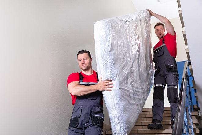 two workers lifting a box spring out of a bedroom in Birmingham MI